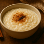 alt_text: Rice Pudding dalam mangkuk, hangat dan menggoda dengan taburan kayu manis di atasnya.